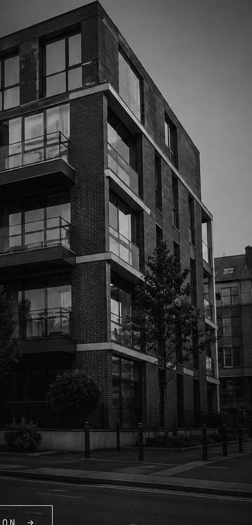 A dark contemporary apartment block in the evening.
